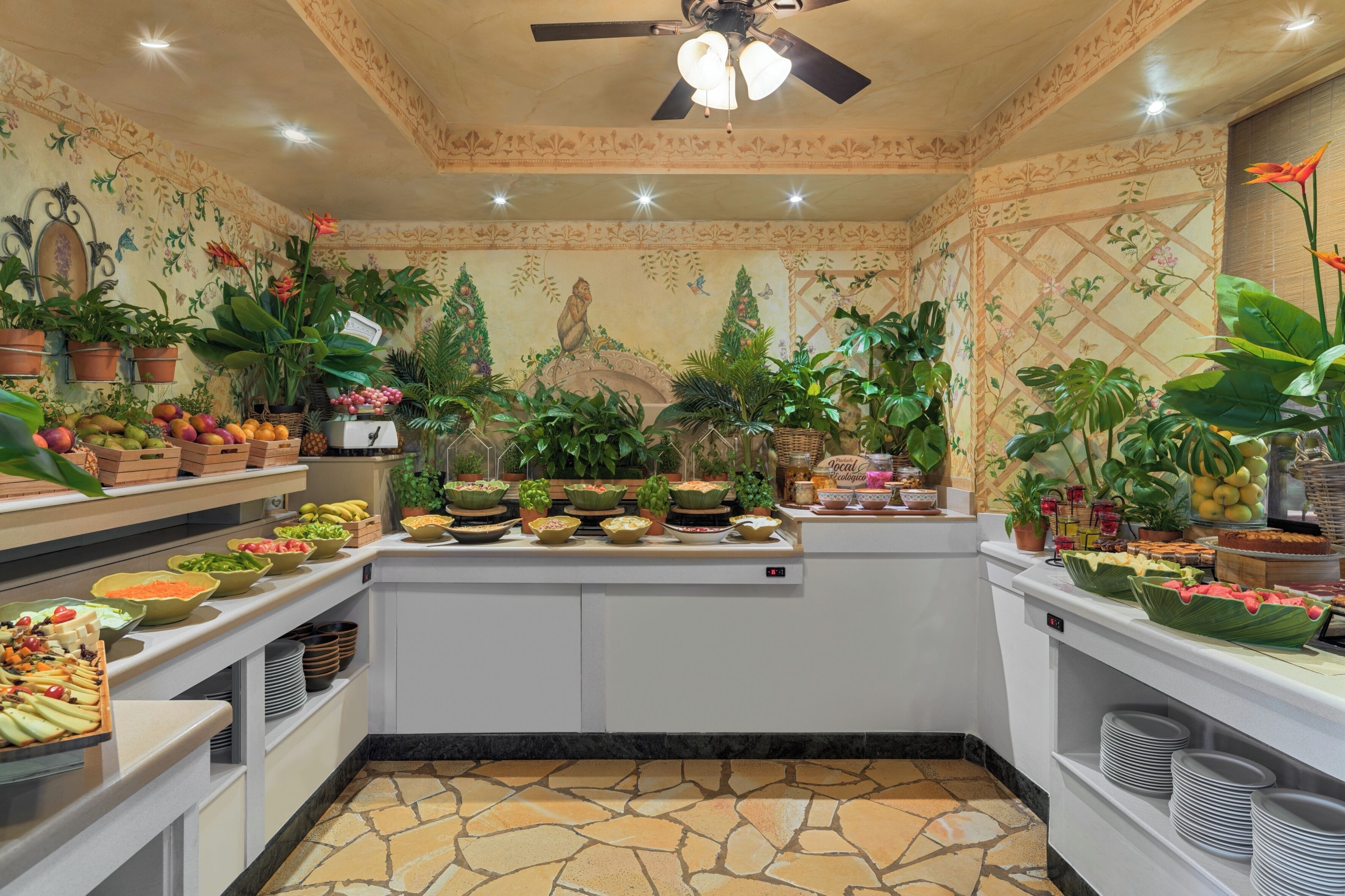 Un área de buffet con diferentes opciones de comida y un mural decorativo en la pared.