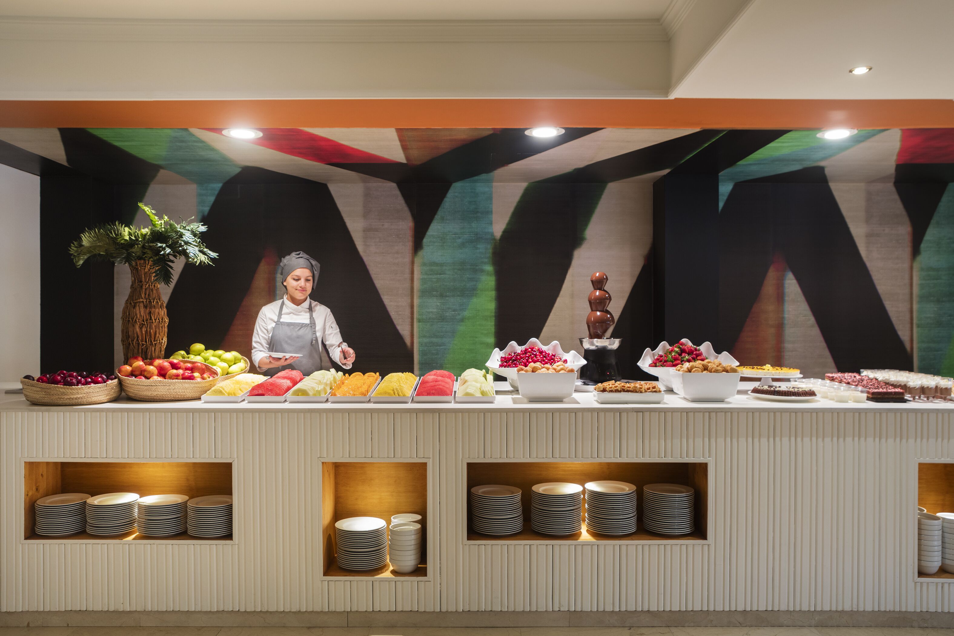 A buffet setup with various food items and a staff member.