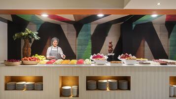A buffet setup with various food items and a staff member.