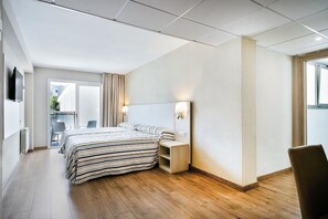 Ett modernt hotellrum med en stor säng, sängbord, en TV och utsikt över omgivningarna.
