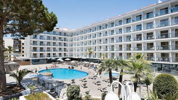 Un hotel amb nombroses balcons, una piscina i gandules.