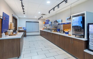 Un área de cocina moderna con cafetera, refrigerador y una encimera con diversos alimentos.
