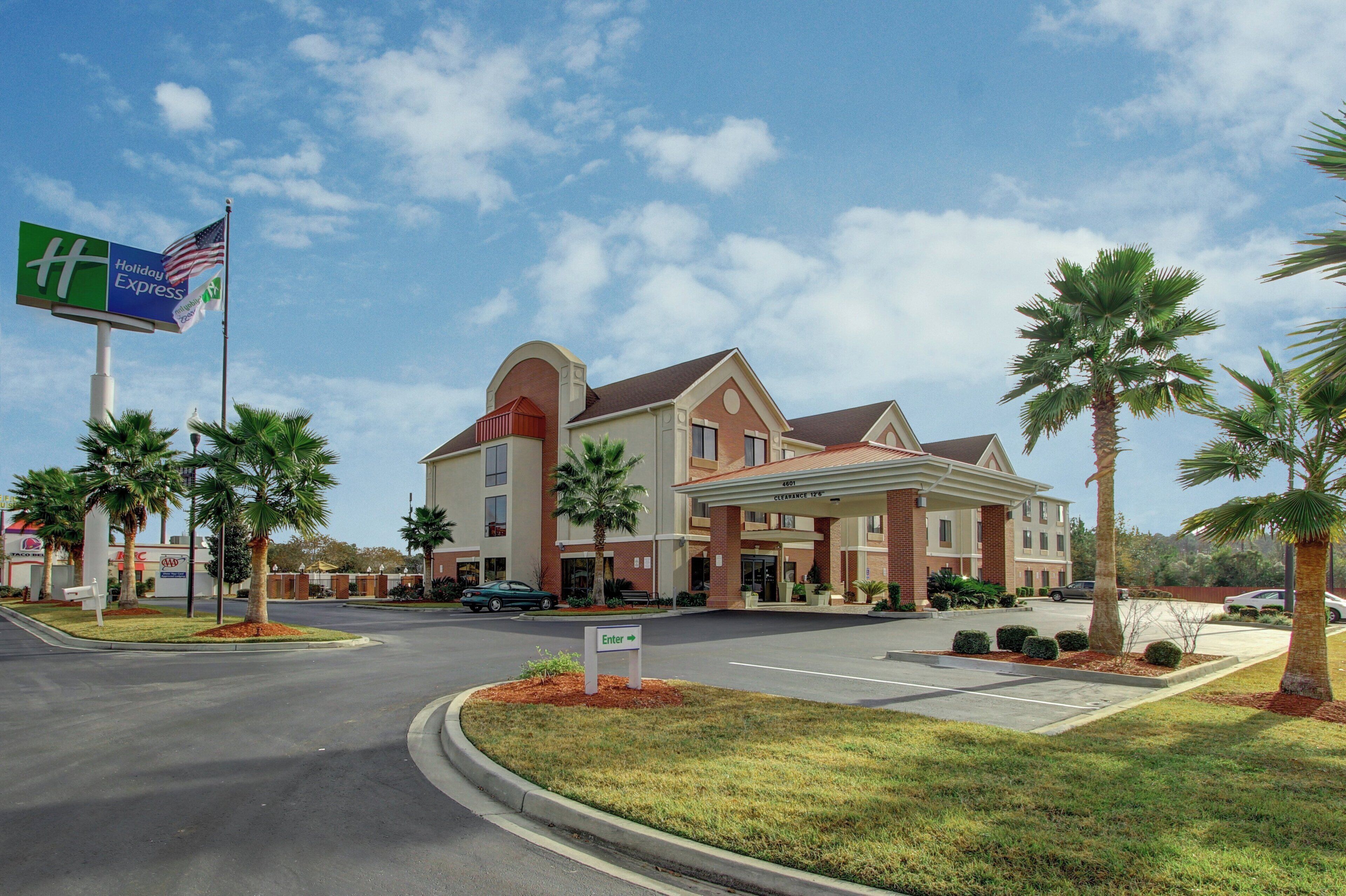 A hotel with a clear entrance, palm trees, and a Holiday Inn Express sign.