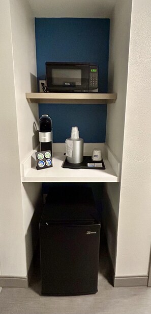 Eine Küchenzeile mit Mikrowelle, Kaffeemaschine und einer Keurig-Kaffeepadmaschine.