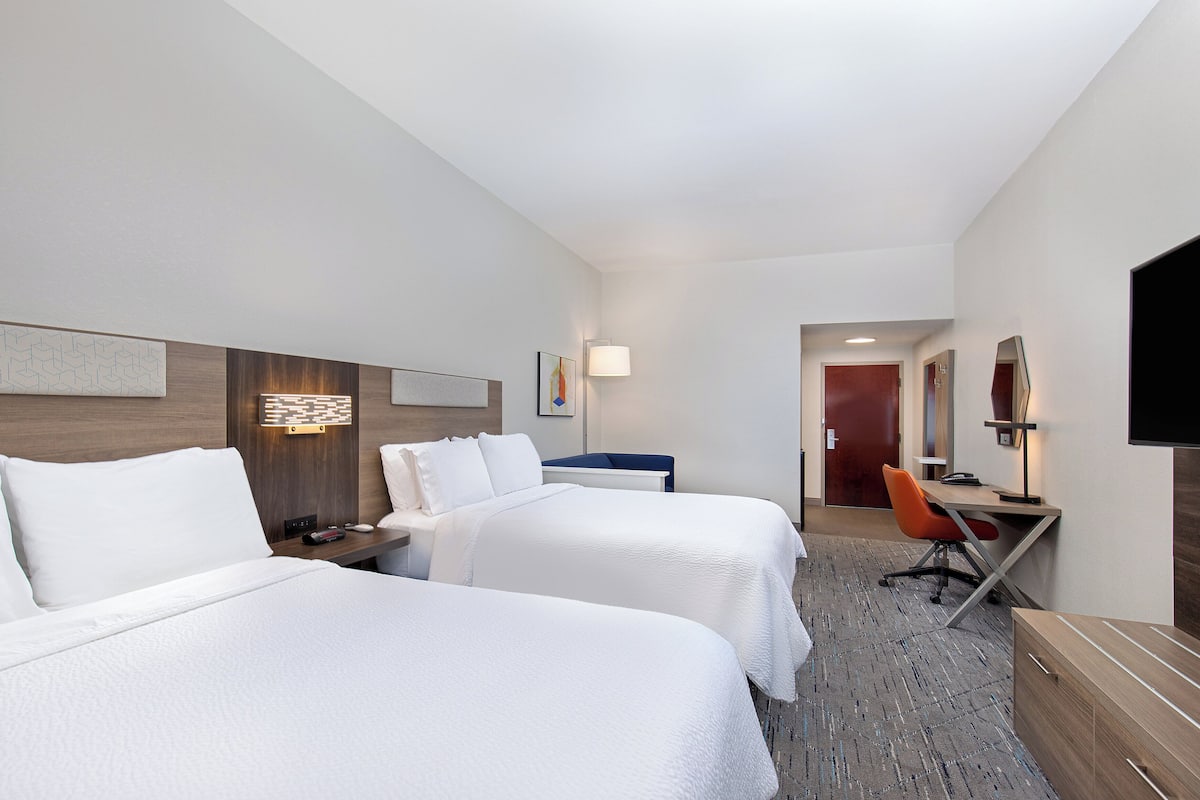 Une chambre d’hôtel avec deux lits, un bureau, une chaise et un téléviseur.