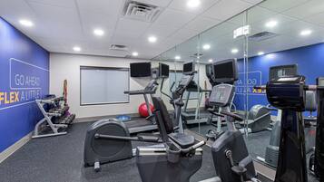 A gym with cardio machines, weights, and a mirrored wall.