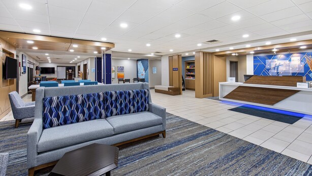 Een moderne hotellobby met een receptiebalie, een zithoek en een pooltafel.