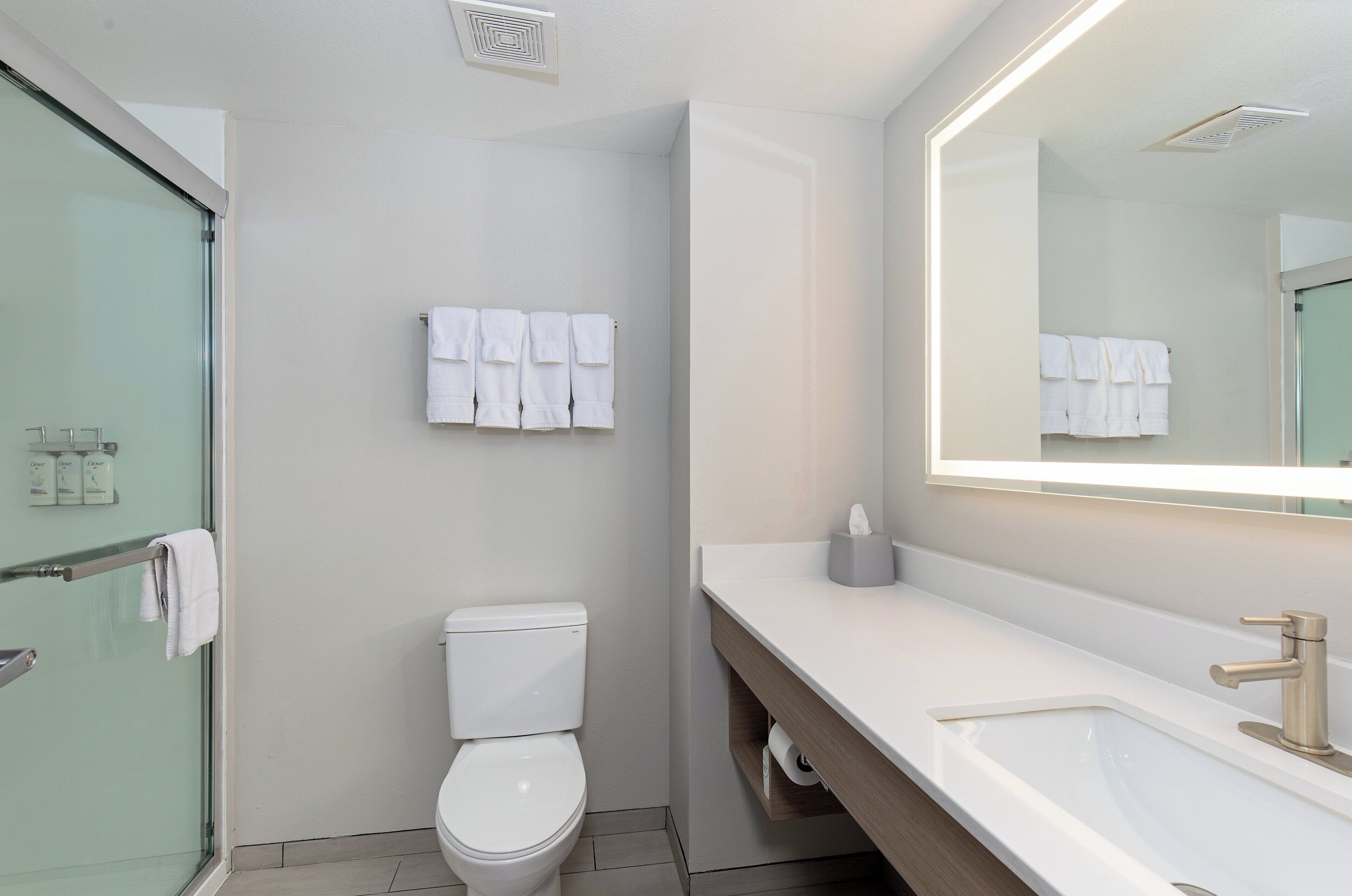 Un baño moderno con inodoro, lavamanos y cabina de ducha de vidrio.