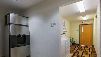 A hallway with a vending machine, an exit sign, and a patterned floor.