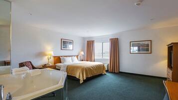 Habitación de hotel con una cama grande, baño independiente con bañera, escritorio y dos cuadros en las paredes.