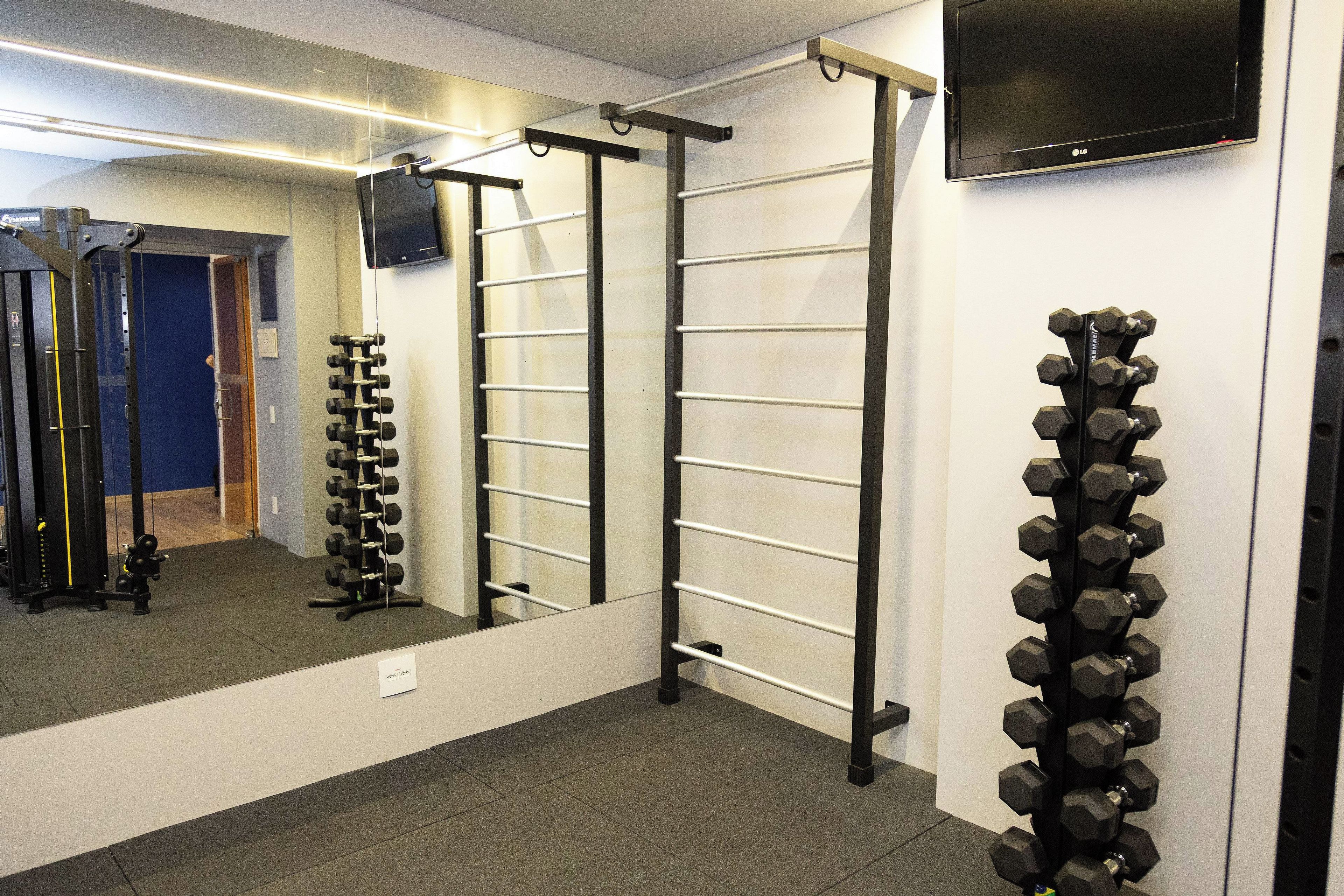 A gym with exercise equipment, a pull-up bar, and a television mounted on the wall.