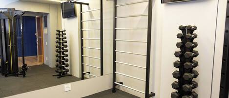 A gym with exercise equipment, a pull-up bar, and a television mounted on the wall.