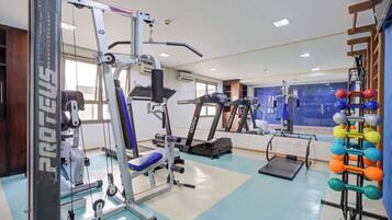 Et fitnesscenter med løbebånd, styrketræningsudstyr og et spejlpanel.