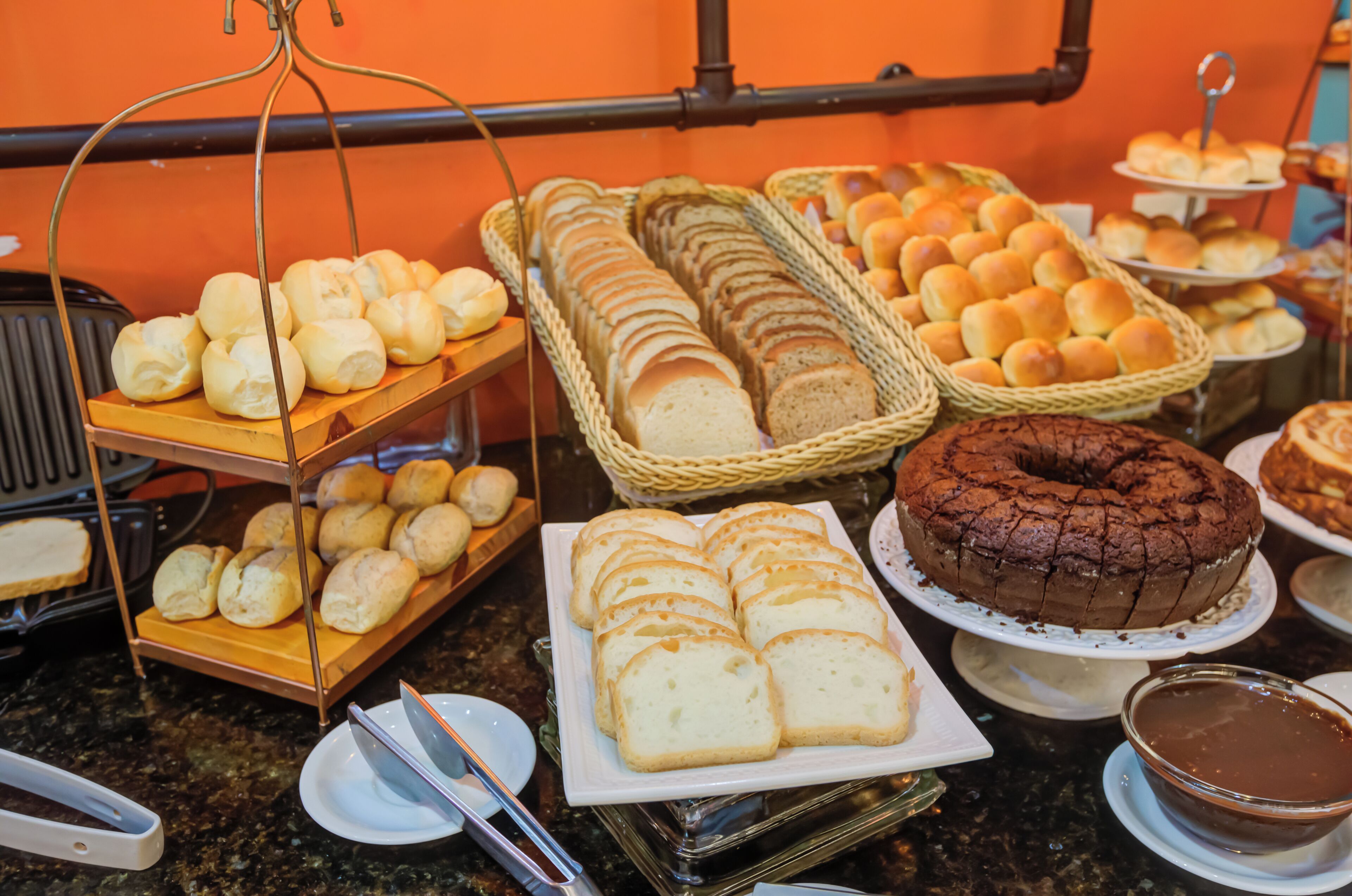 Un buffet con diversi prodotti da forno, tra cui panini, croissant e una torta al cioccolato.