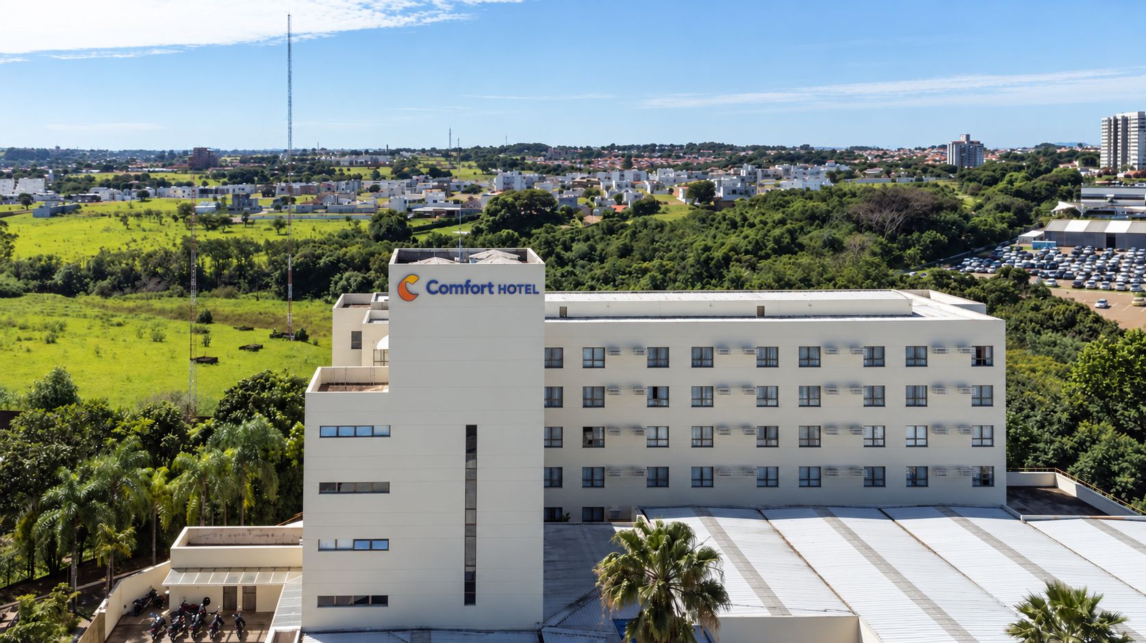 Edificio de Comfort Hotel con techo plano, varias ventanas y un estacionamiento al frente.