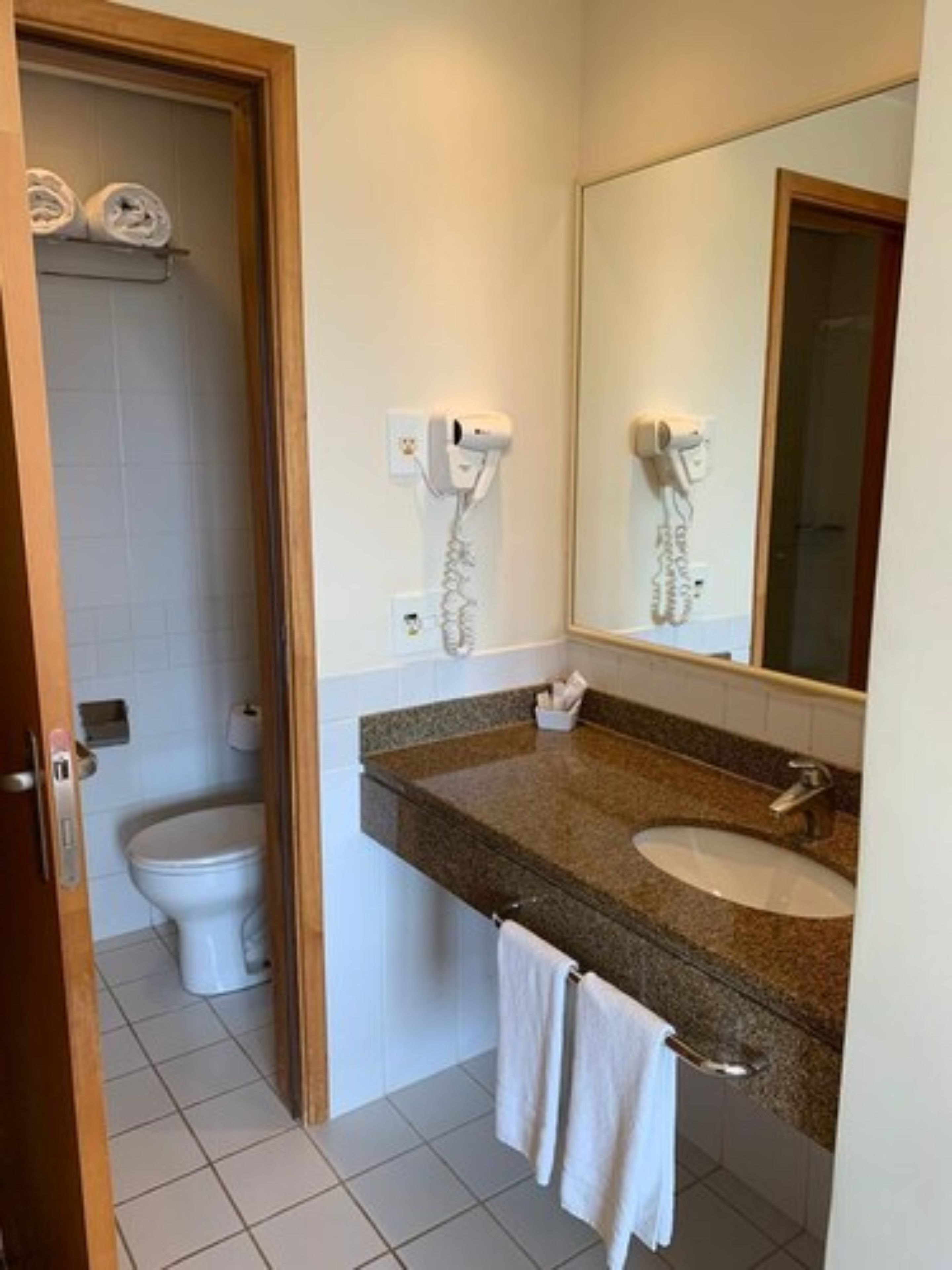 Ein Badezimmer mit Toilette, Waschbecken, Fön und Handtuchhalter.