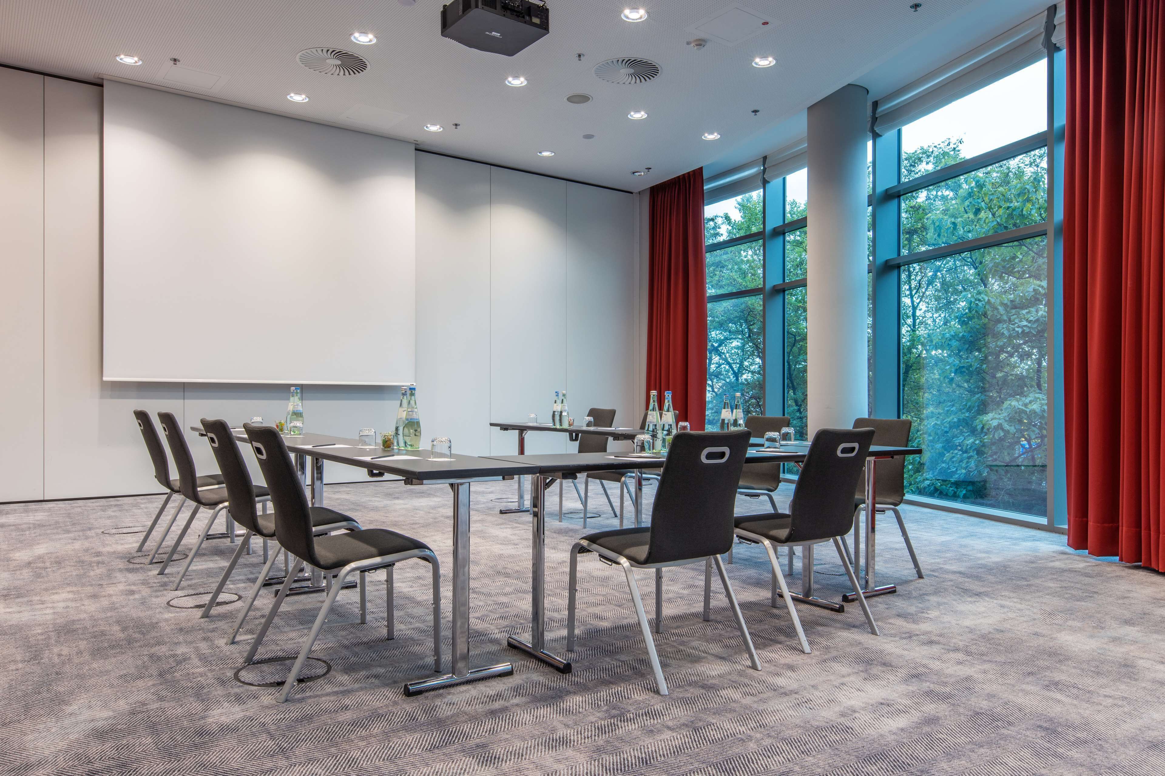 A conference room with a long table, chairs, and a projector screen.