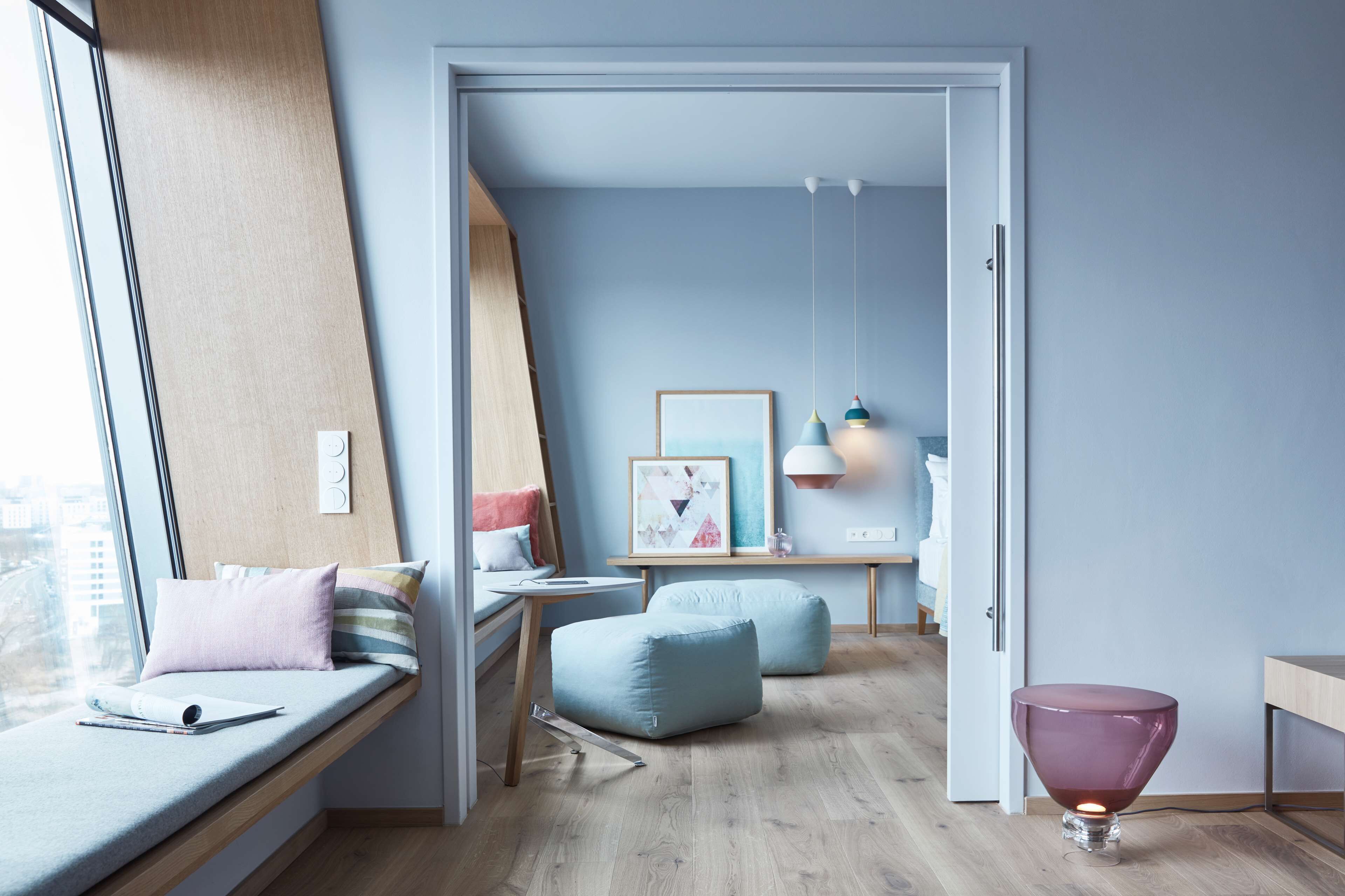 A modern bedroom with a built-in bench, a desk, and a reading area by the window.
