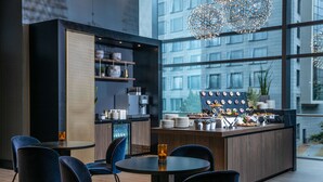 A modern bar area with a central island, bar stools, and a large window offering a city view. - Radisson Blu Hotel, Frankfurt (Frankfurt)