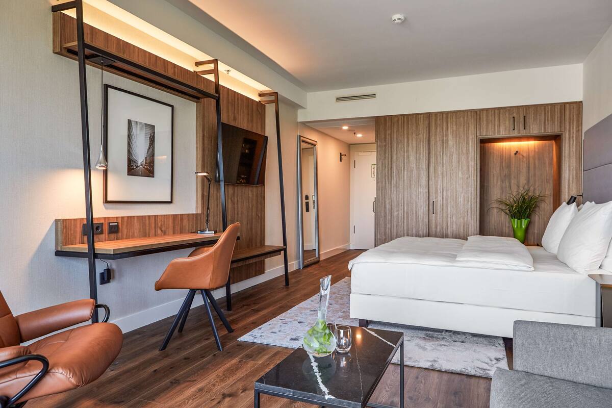 A modern living room with a white sofa, a glass coffee table, and a desk with a chair.