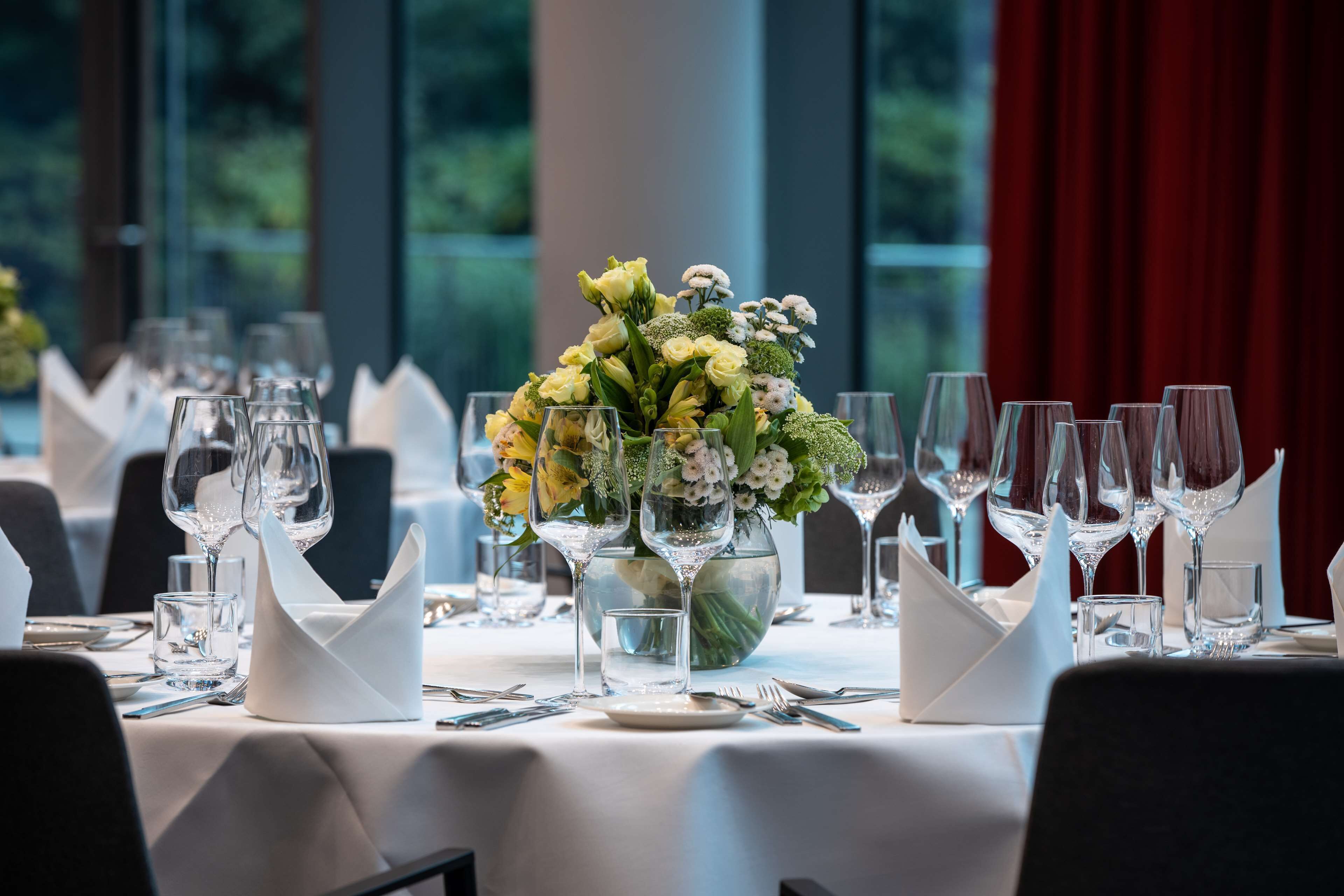 A dining table set with multiple wine glasses, water glasses, and a centerpiece of flowers.