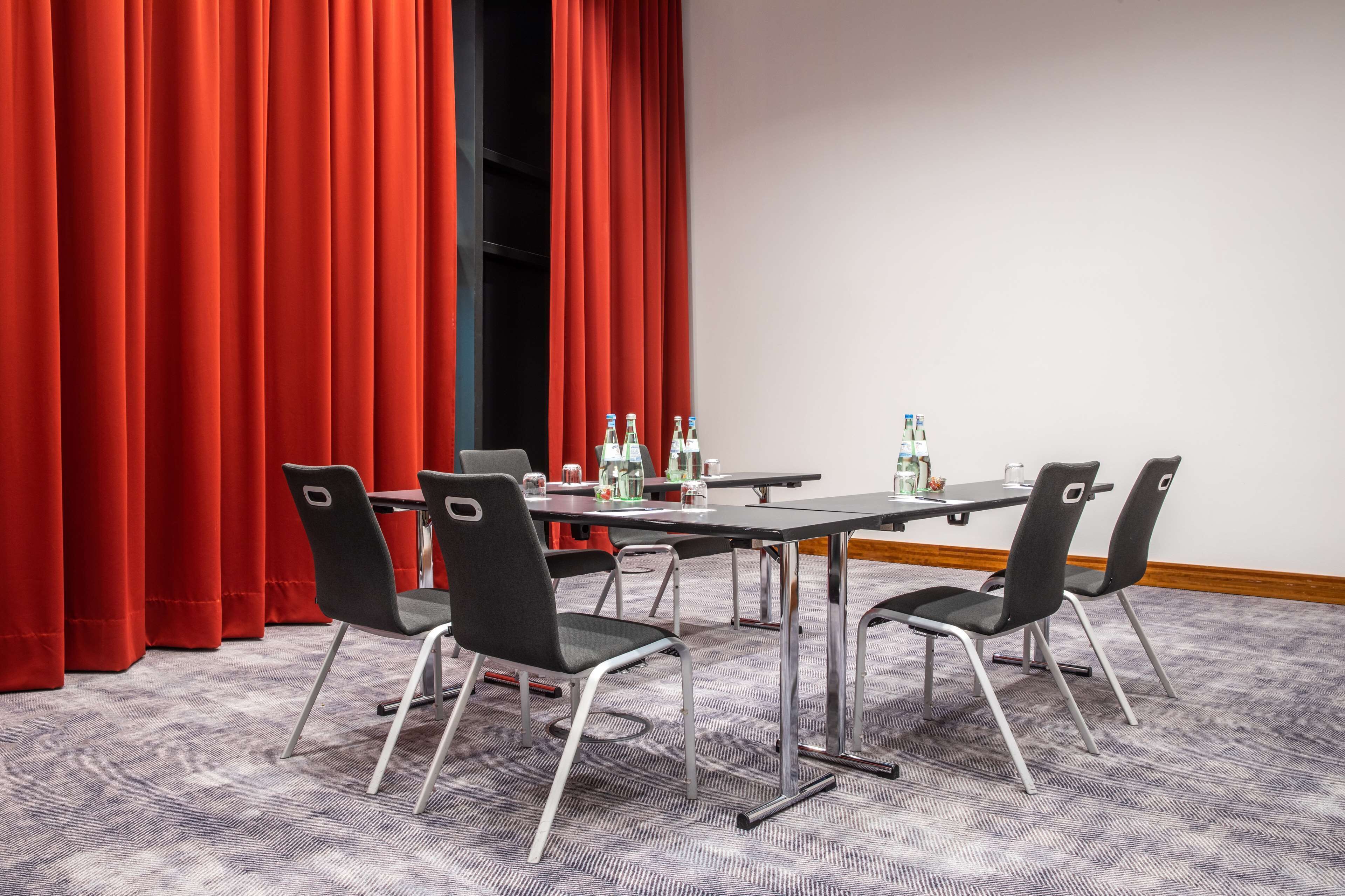 Ein Konferenzraum mit einem langen Tisch, vier Stühlen und Teppichboden.