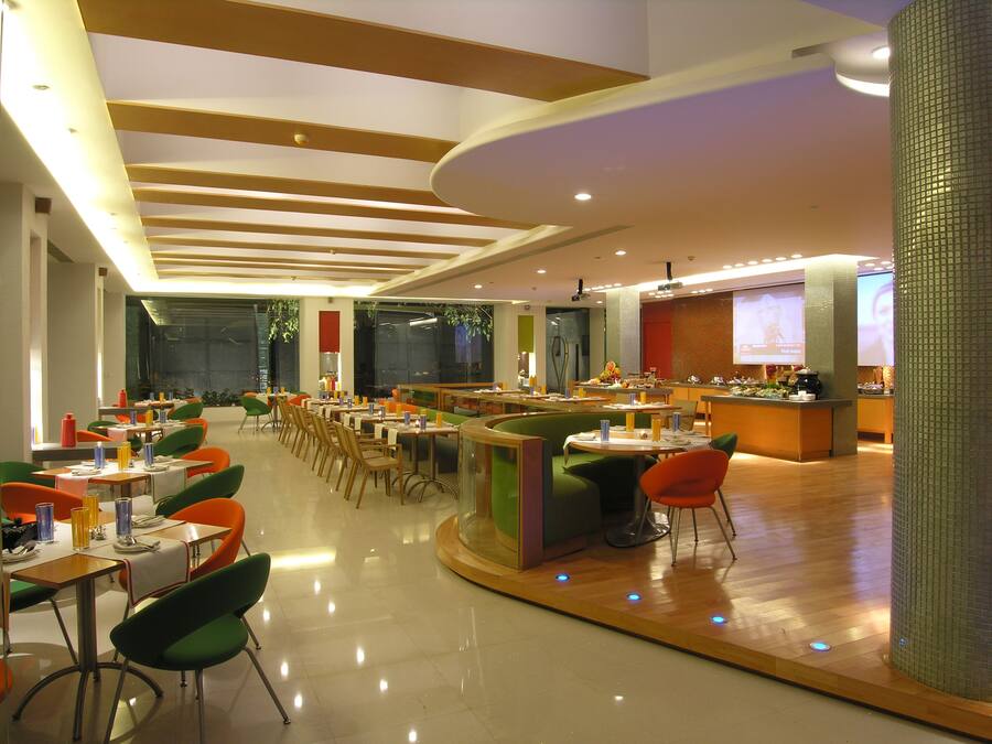 A modern restaurant with a long counter, multiple tables, and chairs.