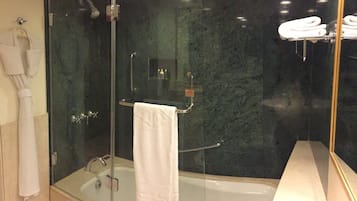 Une douche à parois de verre avec une serviette blanche, une baignoire à parois de verre et un meuble-lavabo à parois de verre avec un porte-serviettes.