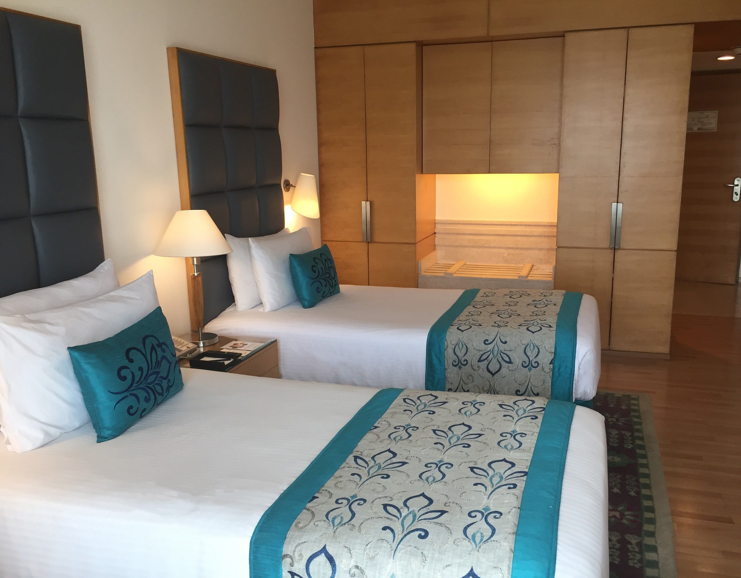 Une chambre d’hôtel avec deux lits, une table de chevet, une lampe et une armoire.