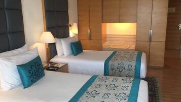 Une chambre d’hôtel avec deux lits, une table de chevet, une lampe et une armoire.