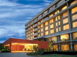Un hotel moderno con fachada plana, varios balcones e ingreso bien iluminado.