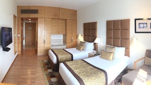 Une chambre d’hôtel avec deux lits, un canapé, une télévision et une grande fenêtre.