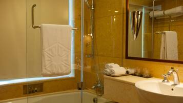 A modern bathroom with a glass-enclosed shower, a white bathtub, and a sink with a mirror above it.