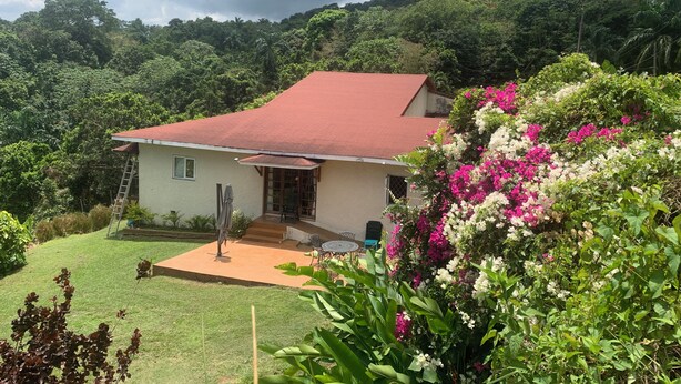 A house with a red roof, a small porch, and a garden with pink and white flowers. - Teresinajamaica (St. Ann's Bay)