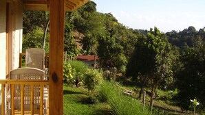 A wooden porch with a view of a lush green landscape and hills in the background. - Teresinajamaica (St. Ann's Bay)