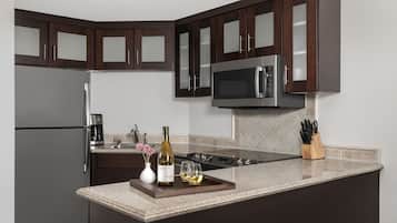 A modern kitchen with dark wooden cabinets, stainless steel appliances, and a granite countertop.