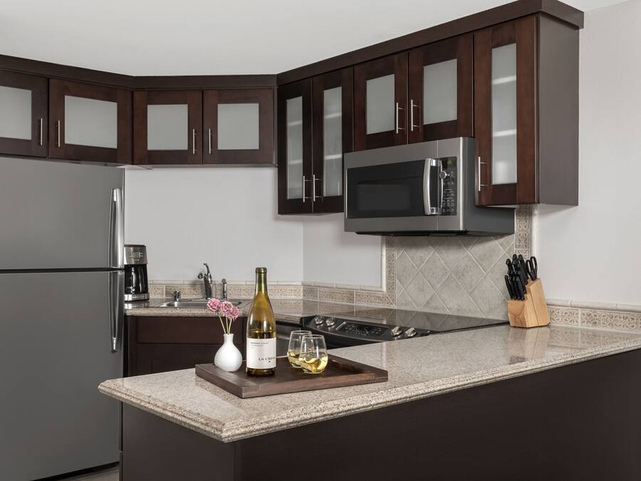 A modern kitchen with dark wooden cabinets, stainless steel appliances, and a granite countertop.