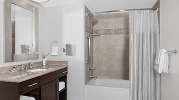 A modern bathroom with a double sink vanity, a glass shower enclosure, and a bathtub.