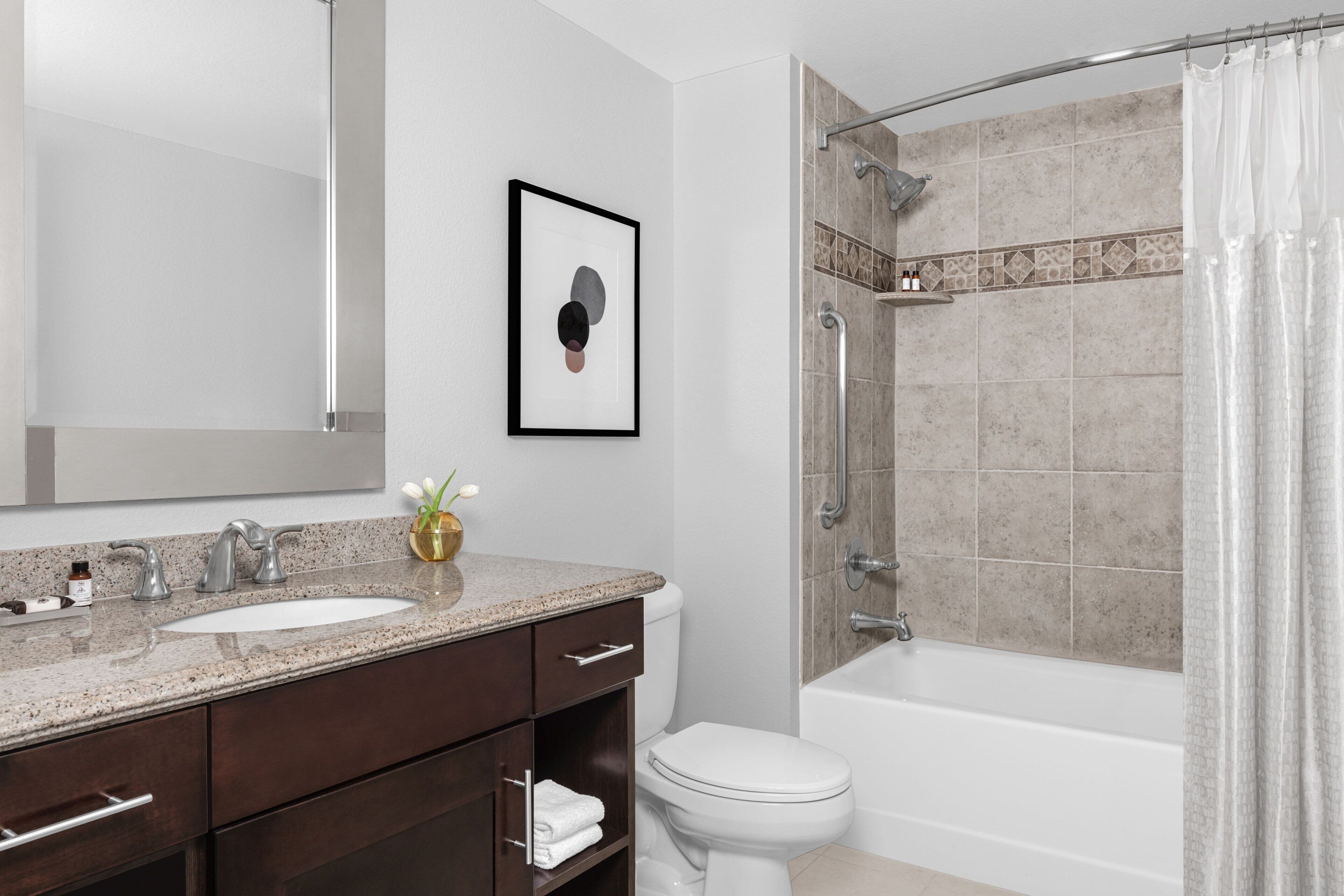 Un bagno moderno con uno specchio grande, un lavandino, un water e una cabina doccia.