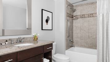 Un bagno moderno con uno specchio grande, un lavandino, un water e una cabina doccia.