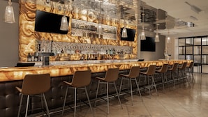 A modern bar area with a marble countertop, multiple bar stools, and a variety of bottles and glasses. - Marriott's Grand Chateau (Las Vegas)