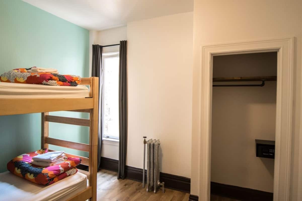 Un letto a castello con biancheria colorata, un termosifone e un armadio con appendiabiti.