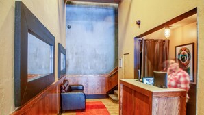 Un hall de hotel con un mostrador de recepción de madera, una alfombra roja y un espejo grande en la pared.