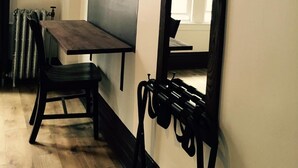 Una habitación con una mesa de madera, una silla, un televisor fijado a la pared y un espejo grande.