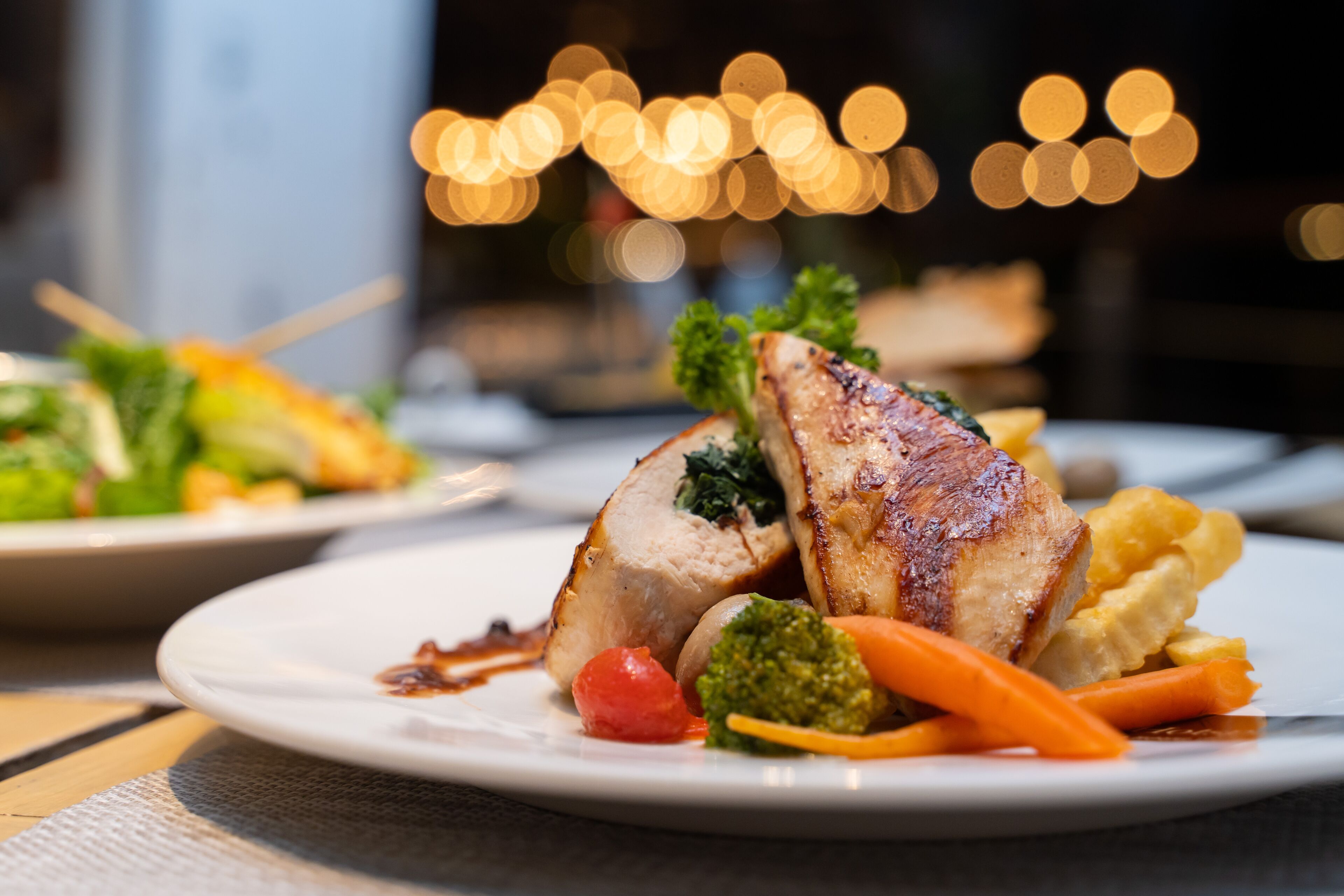 A plate of food with a grilled chicken breast, broccoli, carrots, and mashed potatoes.