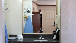 A hotel bathroom with a sink, mirror, and a towel rack. - Sanger Inn (Sanger)