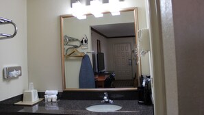 A hotel bathroom with a large mirror, a sink, and a towel rack.