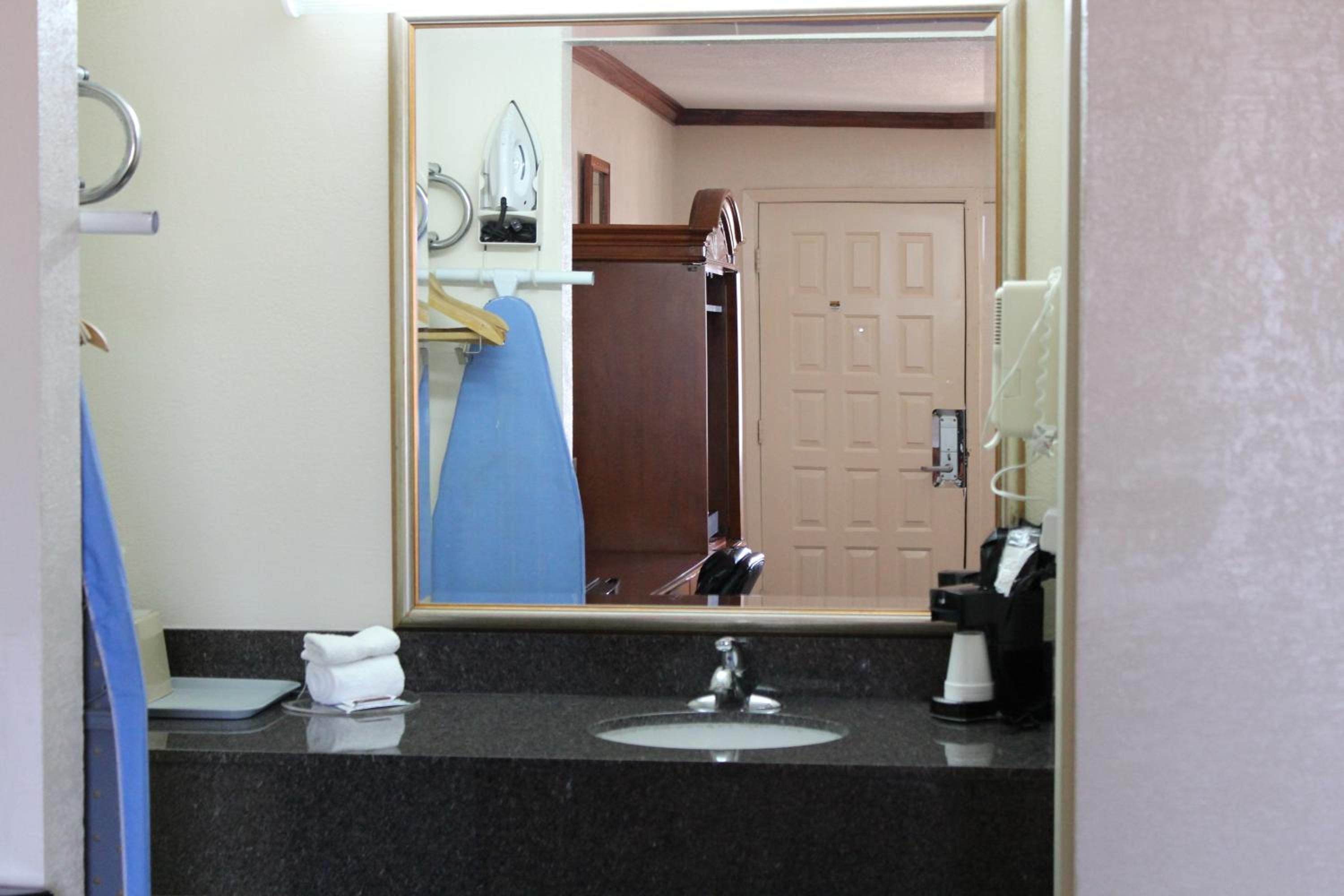 Un bagno d'albergo con lavandino, specchio e porta asciugamani.