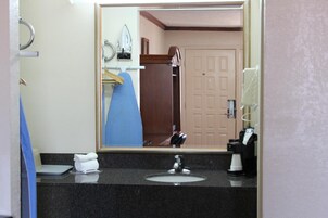 A hotel bathroom with a sink, mirror, and a towel rack.