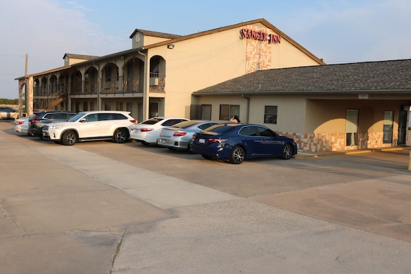 A motel with a row of parked cars and a building with a sign reading "Sanger Inn".